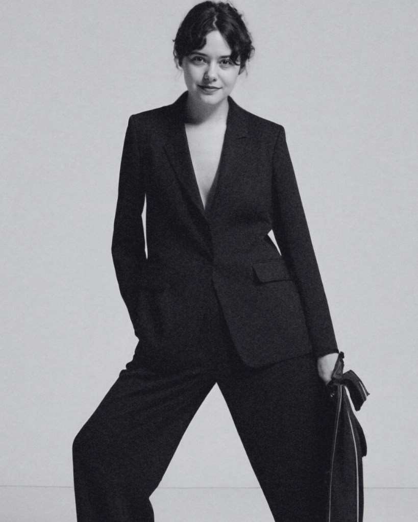 Editorial portrait by Jenna Brooke featuring model in tailored black suit against minimalist backdrop.